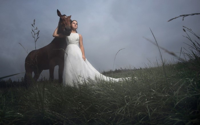 Woman in white dress with horse in grassy field