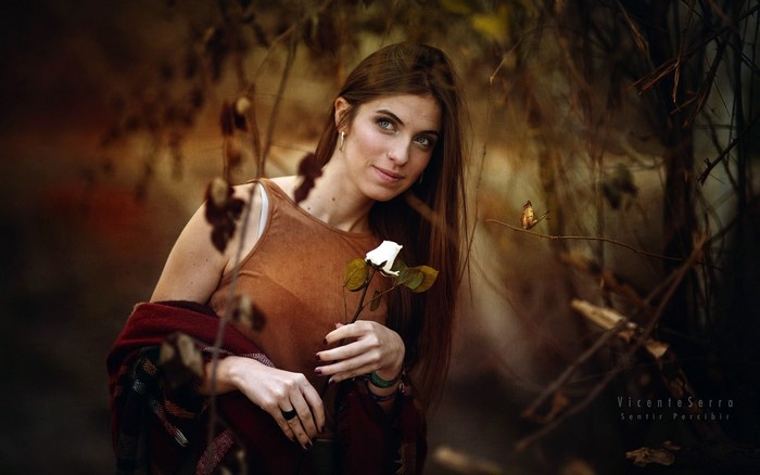 Woman holding a white rose in a dark forest
