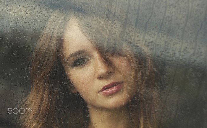 Woman looking through a rain-streaked window