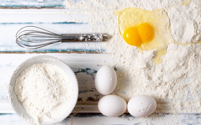 Baking ingredients: flour, eggs, and whisk