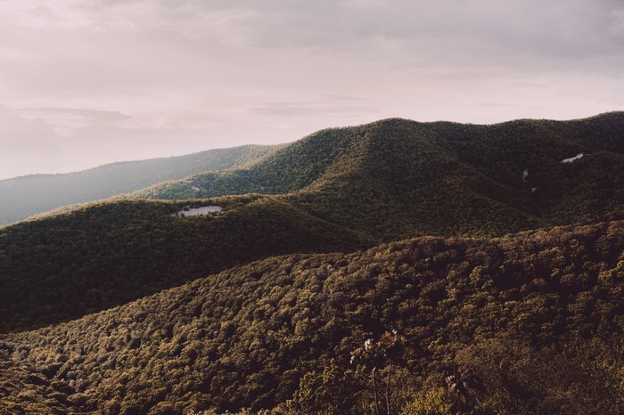 Green forested mountains under a cloudy sky