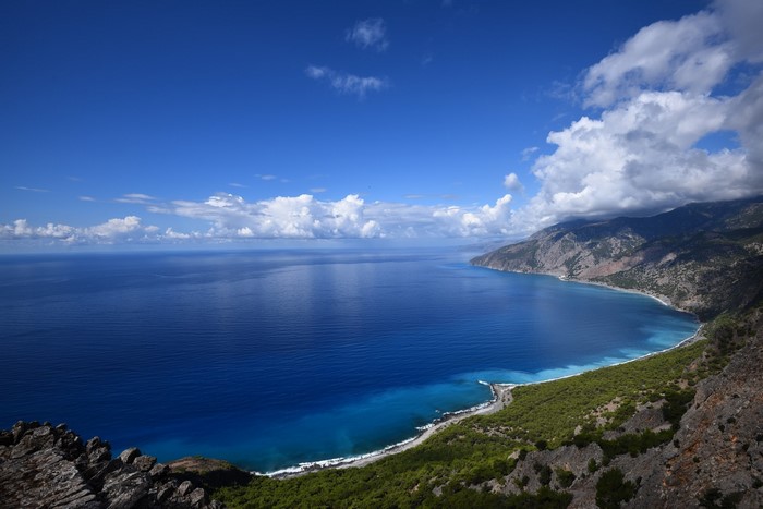 Blue sea and mountains along the coast under a cloudy sky