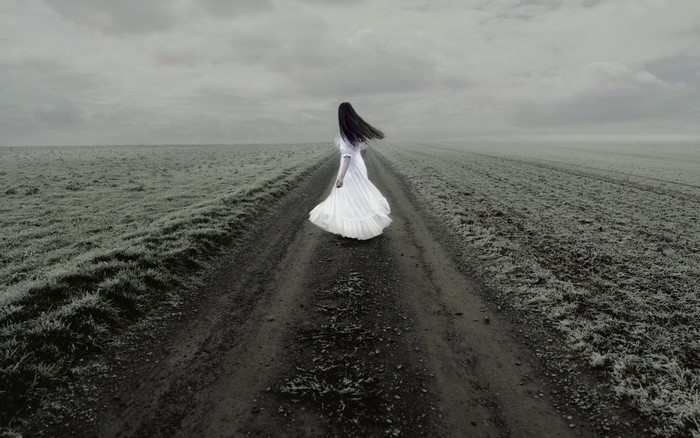 Woman in white dress on a dirt road in a field