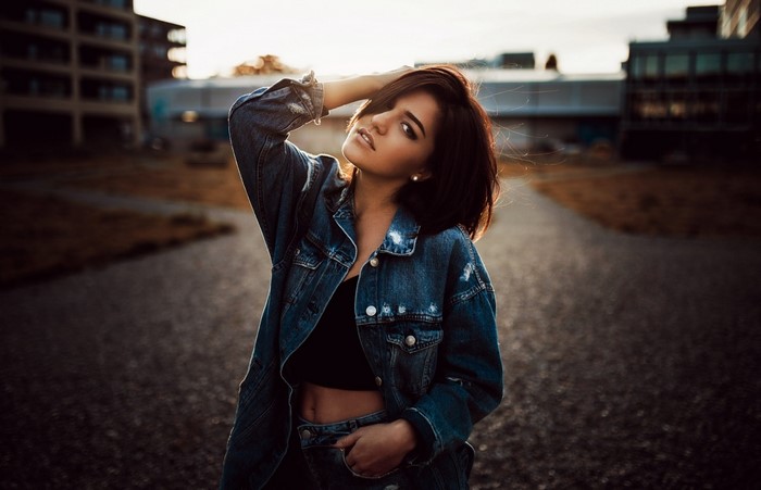 Woman in denim jacket posing outdoors at sunset