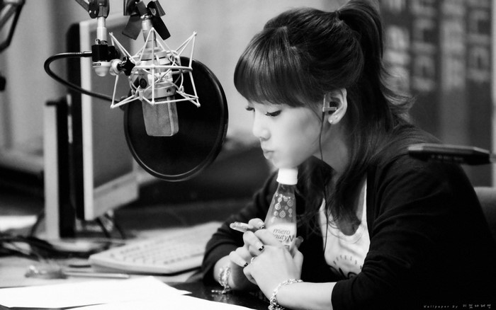 Woman drinking from a bottle in front of a microphone