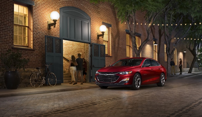 Red Chevrolet Malibu RS parked outside brick building at night