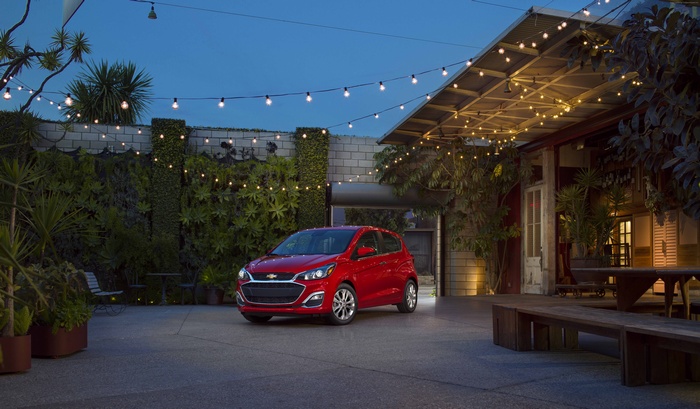 Red Chevrolet Spark parked in a courtyard at dusk