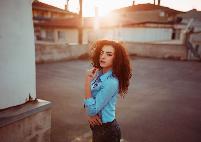Woman with curly hair wearing a blue shirt and jeans