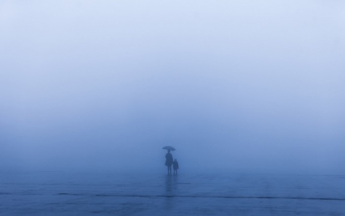 Two figures with an umbrella in the fog
