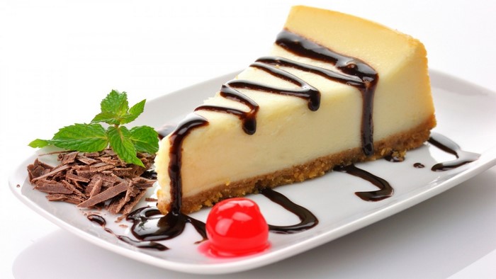 Slice of cheesecake with chocolate drizzle and cherry