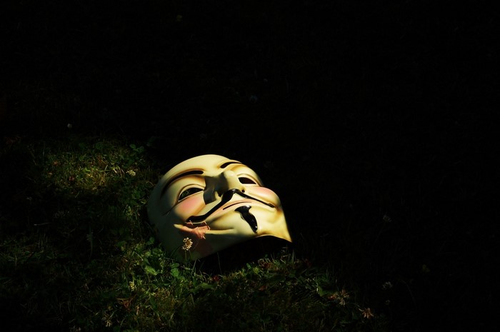 Guy Fawkes mask on grass in darkness