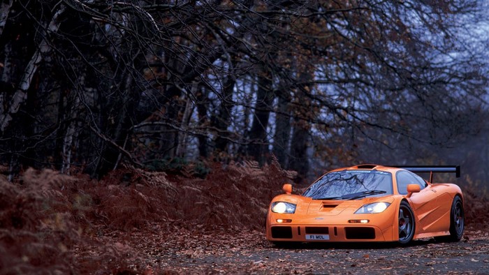 Orange McLaren F1 GTR parked on a forest road in autumn