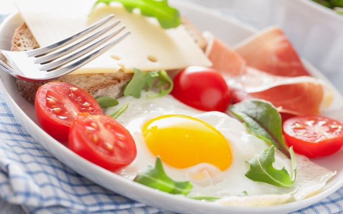 Fried egg with prosciutto, cheese, tomatoes, and bread