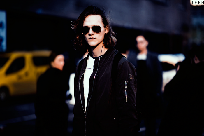 Man with long hair wearing sunglasses and bomber jacket