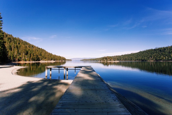 Wooden dock on a clear lake surrounded by forests