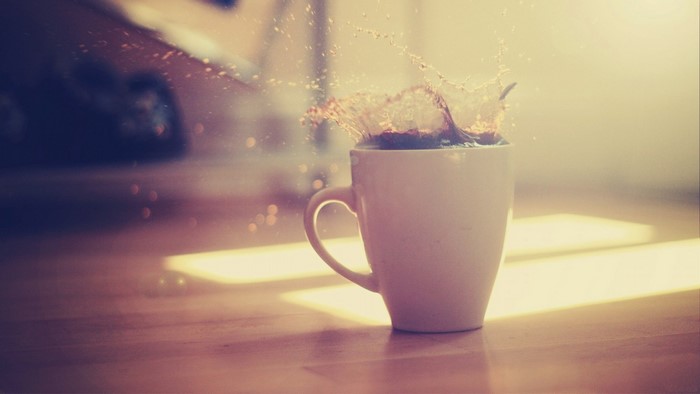 Coffee splash in a white mug with light reflections