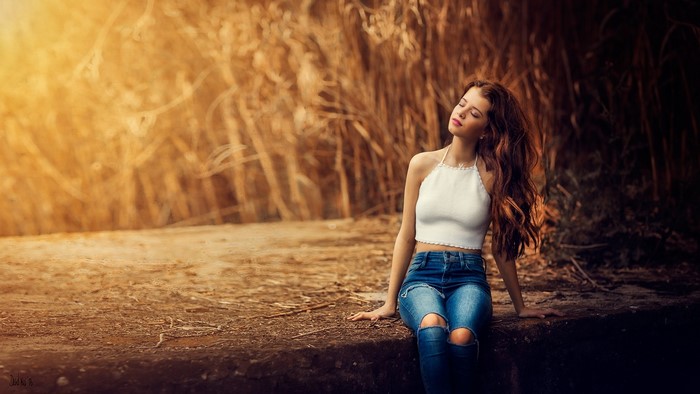 Woman with long wavy hair sitting outdoors