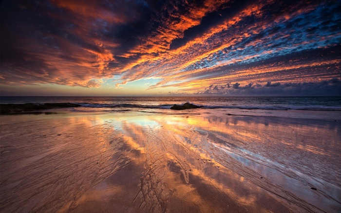 Sunset over a beach with colorful clouds and reflections
