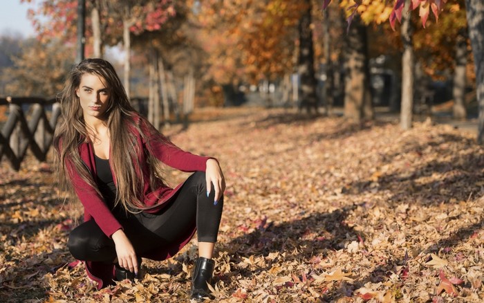 Woman in Red Sweater Posing in Autumn Leaves