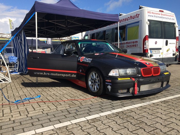 Black BMW E36 race car with red and gold stripes