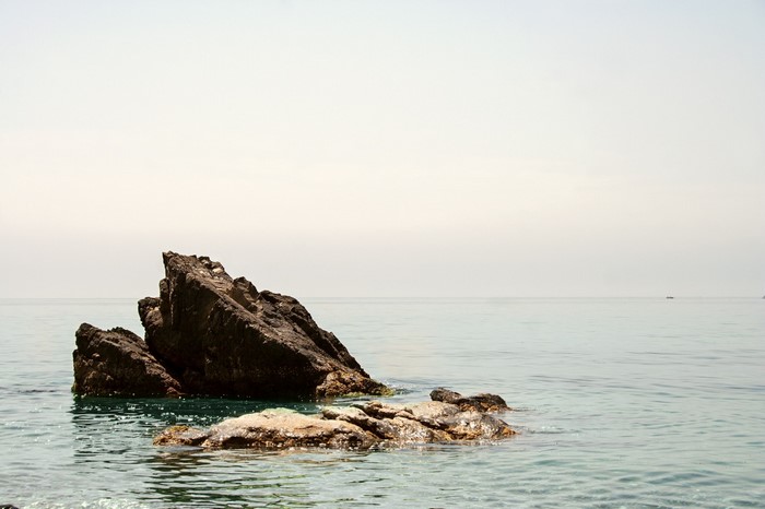 Rocks in the sea with a distant boat on the horizon