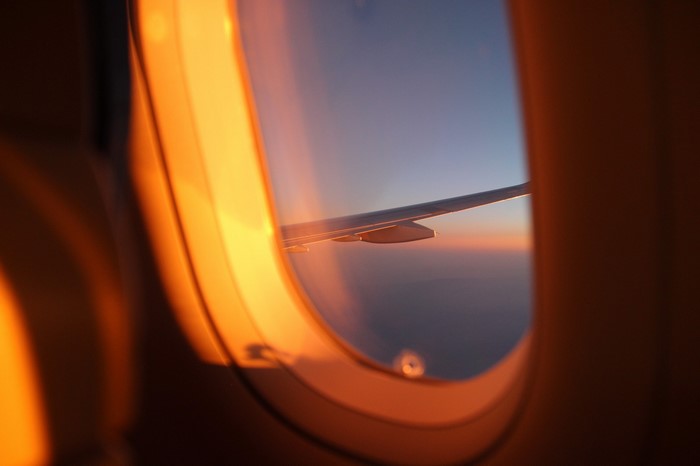 Airplane window view at sunset with wing