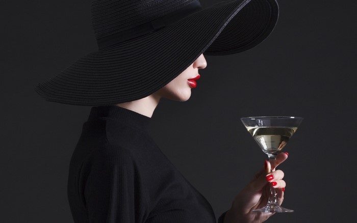 Woman in black hat holding a martini glass