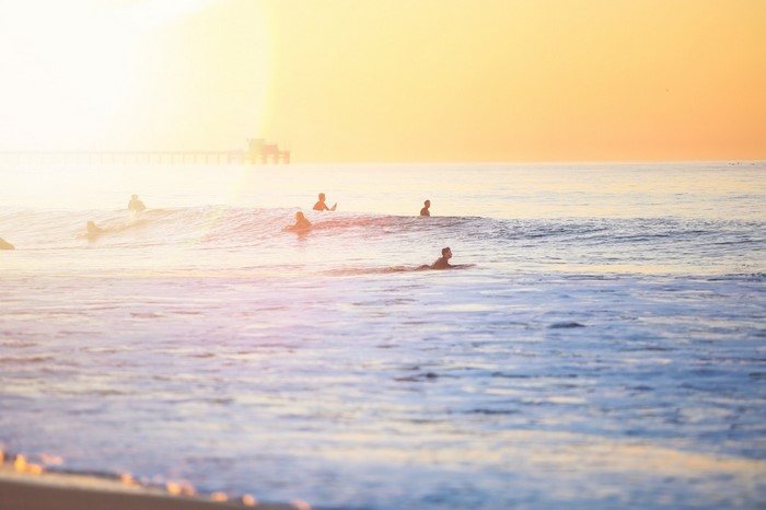 Surfers on waves at sunset with pier in background