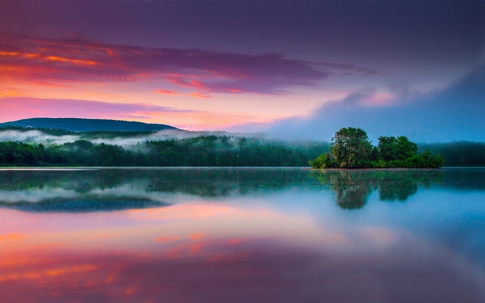 Sunrise over a misty lake with an island