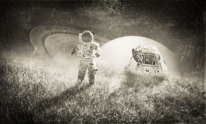 Astronaut and spacecraft on a grassy field with Saturn in the background