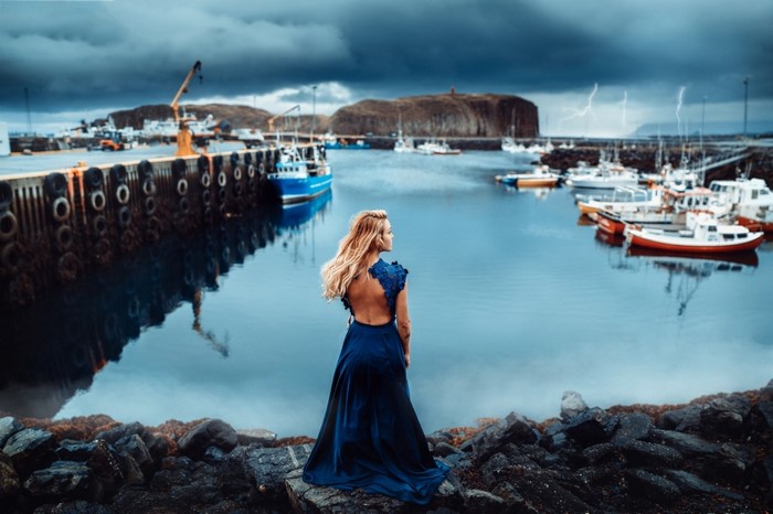 Woman in blue dress at a harbor with boats