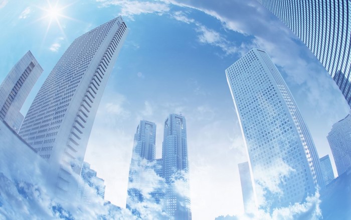 Skyscrapers reflecting clouds against a bright blue sky