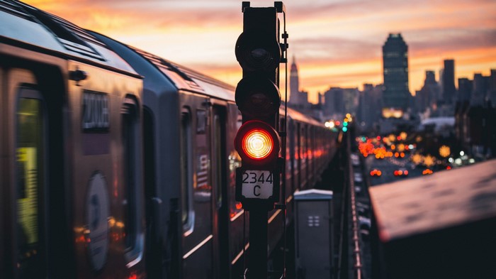 Train passing a traffic light in New York City at sunset