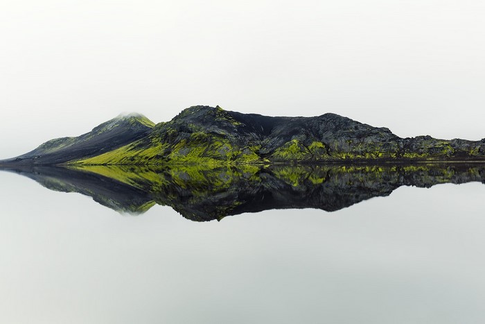 Mossy volcanic mountains reflected in still water