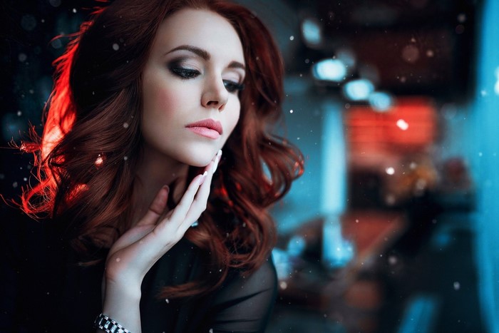 Woman with auburn wavy hair and dramatic makeup