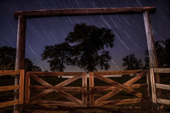 Wooden gate under star trails at night