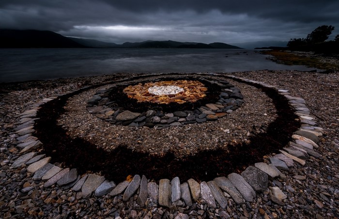 Stone mandala on a rocky shore with dark clouds