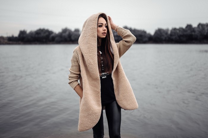 Woman in hooded coat by the water