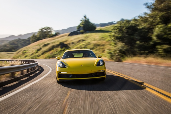 Yellow Porsche 718 Cayman GTS driving on a winding road