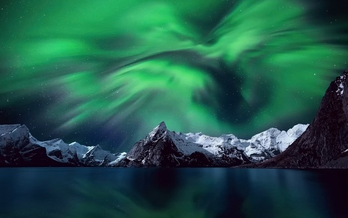 Aurora Borealis over snowy mountains and lake
