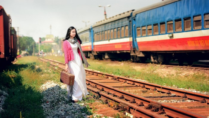 Woman with suitcase walking on train tracks