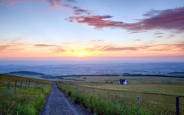 Rural landscape at sunrise with a dirt path and a house