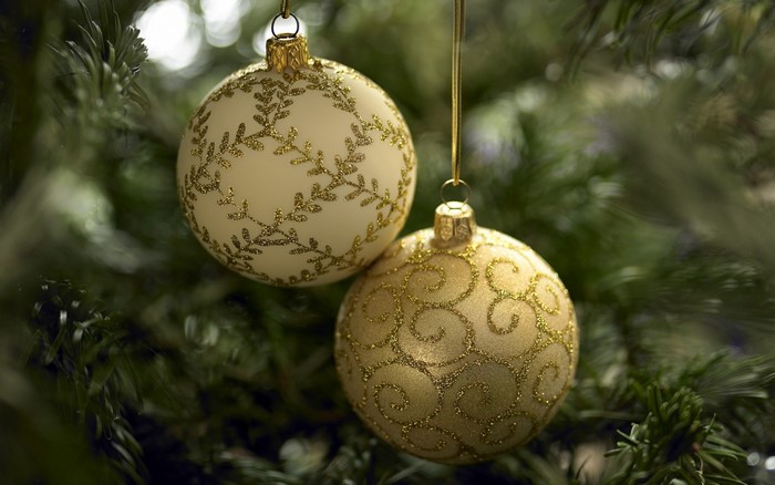 Two Christmas ornaments hanging on a fir tree