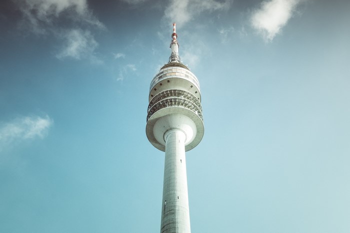 Television tower against a blue sky with clouds