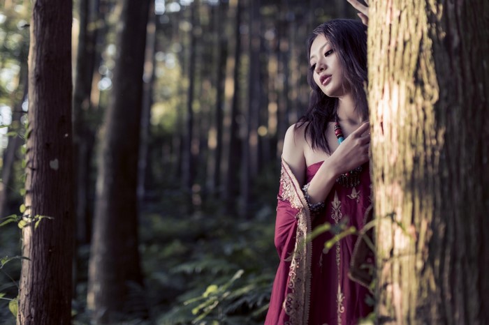Asian woman in a red dress in a forest
