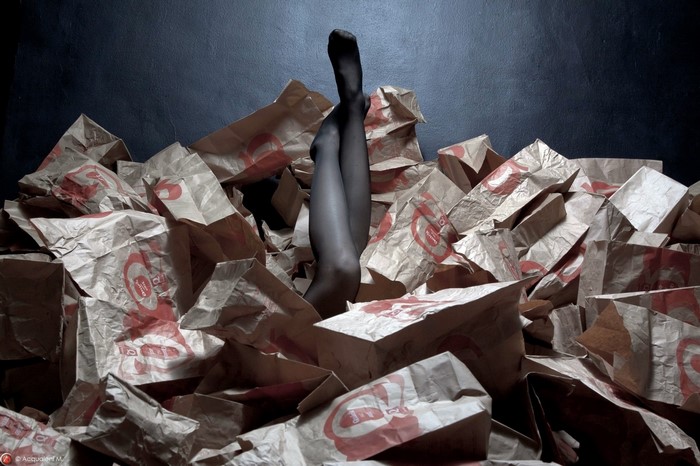 Woman's legs emerging from a pile of paper bags