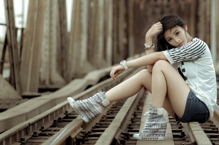 Asian woman sitting on train tracks