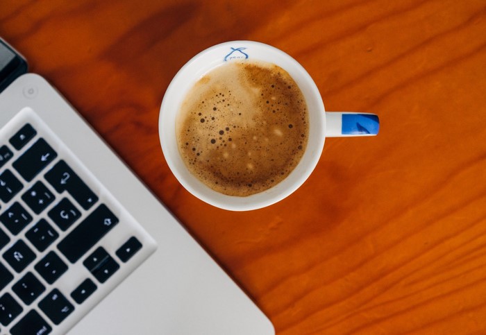 Espresso cup next to a laptop on a wooden table