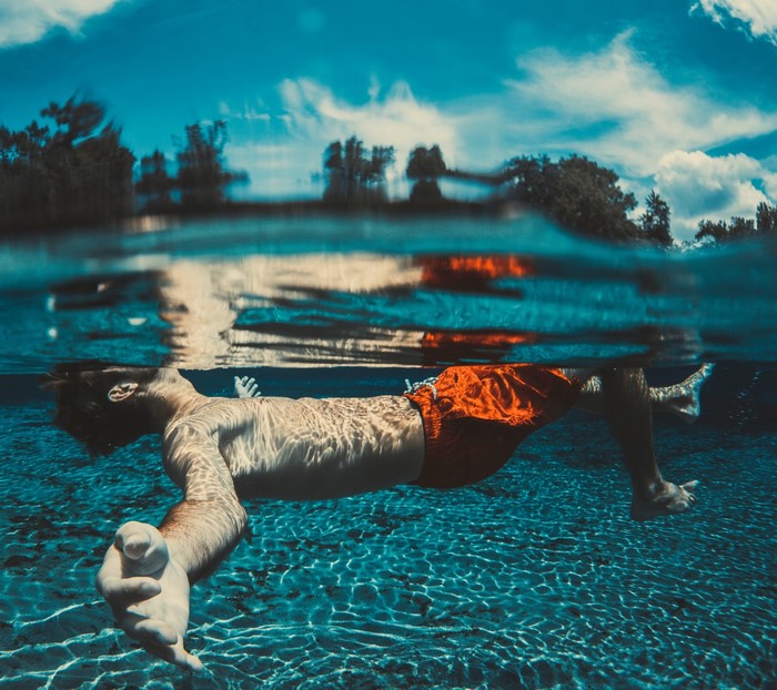 Man floating underwater in a pool