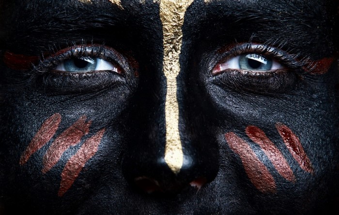 Close-up of a woman with black and gold face paint